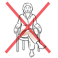 Front view of person sitting in chair with legs crossed, and red X shows not to do this.