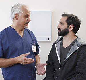 Hombre en una sala de examinación hablando con un proveedor de atención médica.