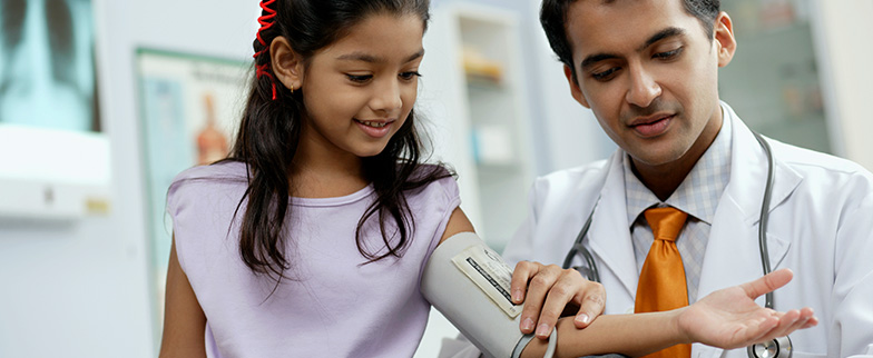 Child having blood pressure taken in doctors office.