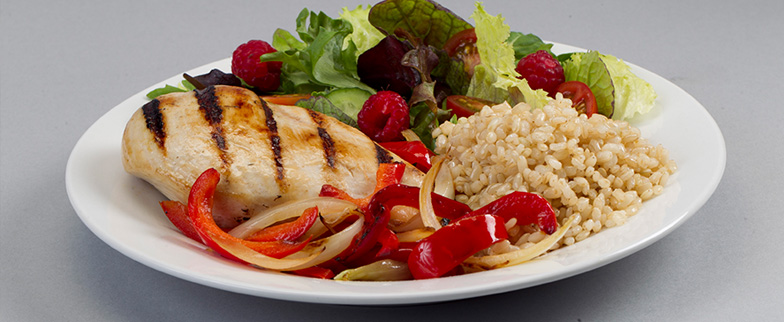 Meal plate with chicken, rice, vegetables and fruit.