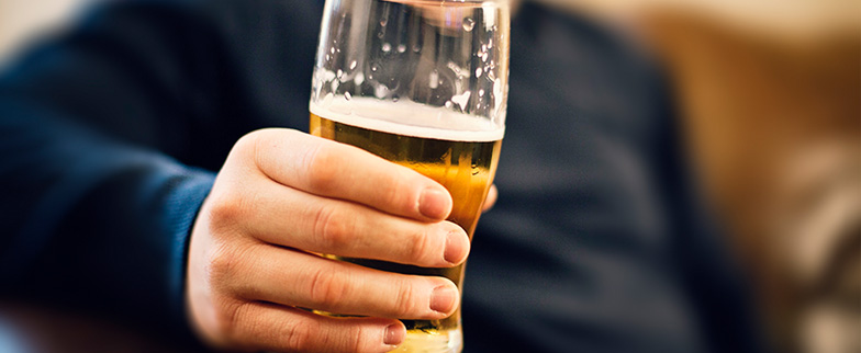 Person enjoying a beer at home on couch.