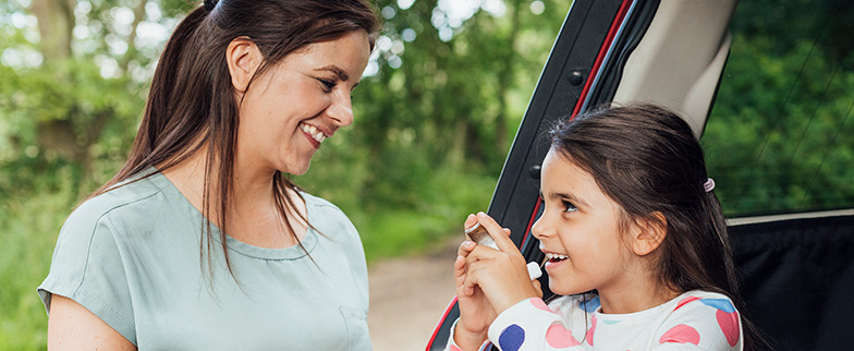 Child outside with parent using inhaler.