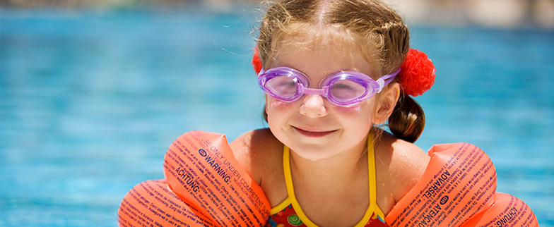 Child by pool with floats on.