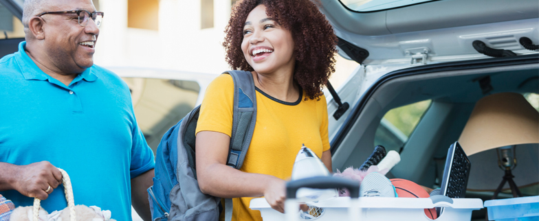 Dad and teen packing a car with luggage