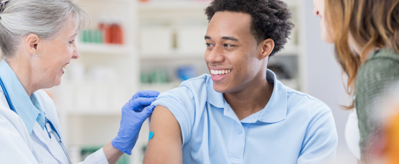 adult with a band aid on their arm smiling at their doctor after getting a flu shot.