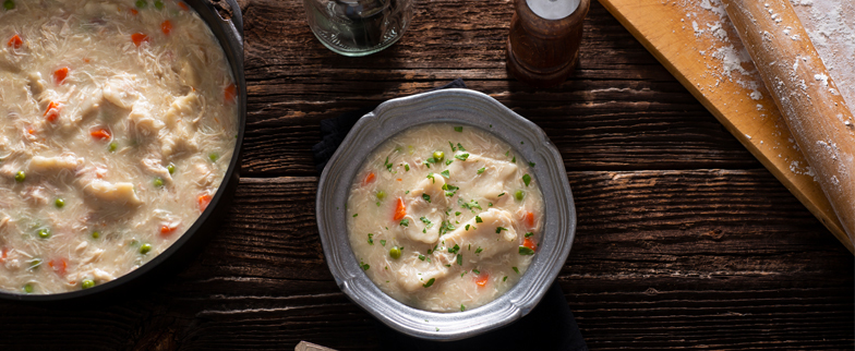 A large bowl of southern chicken and dumpling soup next to a smaller bowl of chicken dumpling soup.