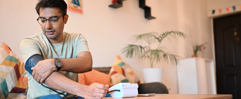 Adult checking their blood pressure at home with an at home blood pressure machine.