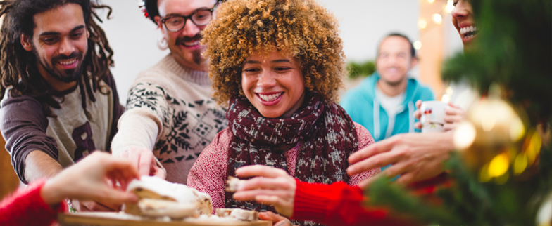 Group of friends at a Christmas party eating Christmas treats from a plate their friend is holding.  