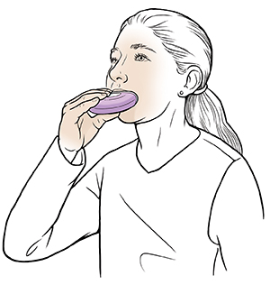 Young woman using dry powder inhaler.